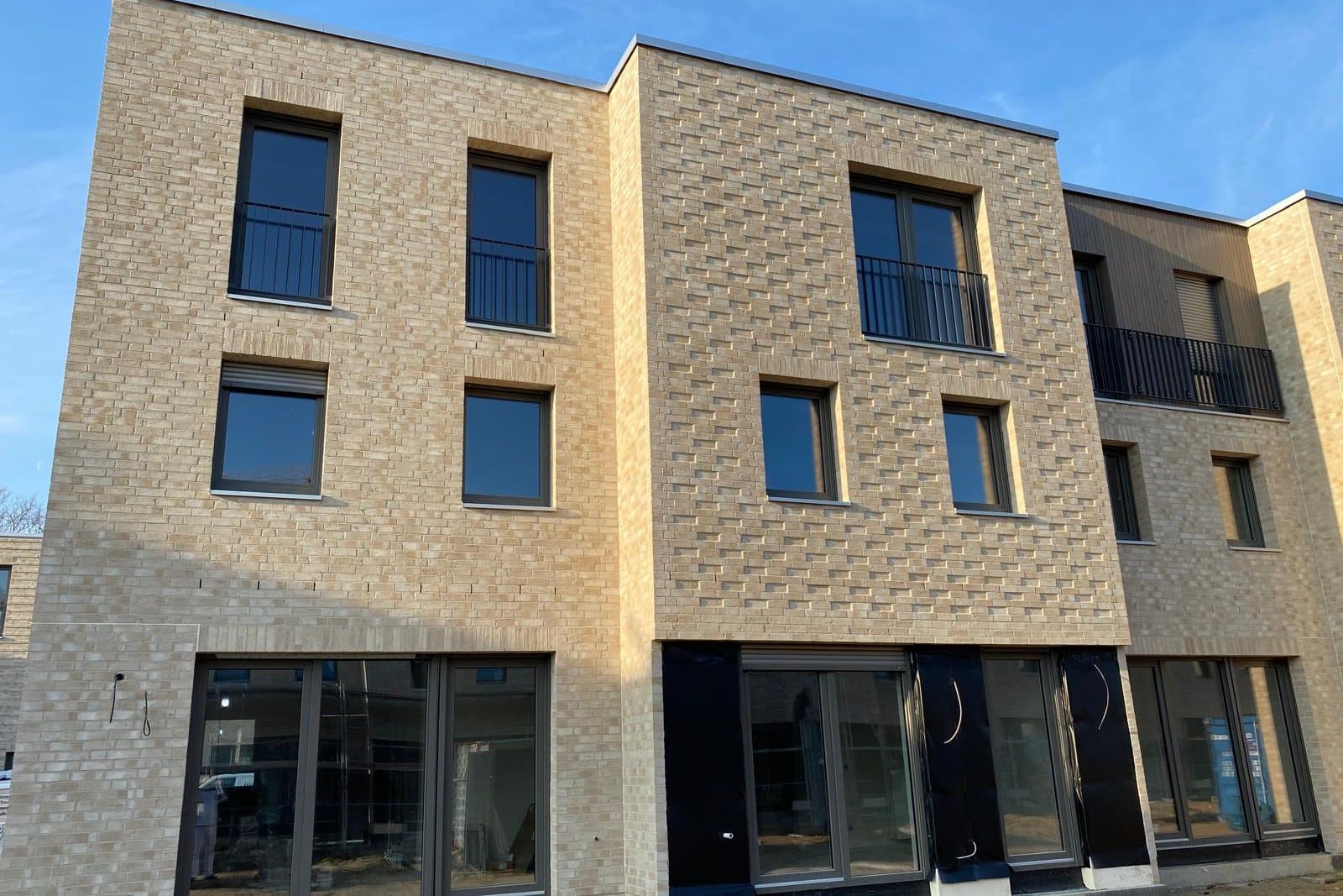 Fertiggestellte Reihenhäuser mit heller Verblendfassade und großen dunklen Fenstern